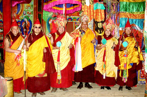 Hor shul Khenpo Gelek Palsang Rinpoche poses in a shrine hall with khenpos and tulkus of Hor shul Monastery, all wearing ceremonial robes.