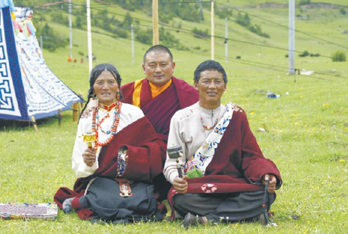 Hor shul Khenpo Gelek Palsang Rinpoche, wearing monastic robes, sits on grass with his parents for a portrait.