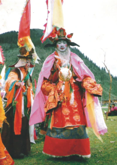 Hor shul Khenpo Gelek Palsang Rinpoche performs the King Gesar vajra dance on grass, wearing a colorful ritual costume and mask.