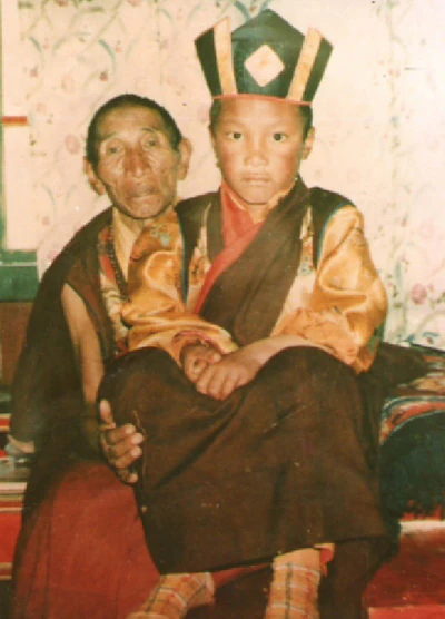 The Seventeenth DB Dharma King holds the young Sangjie Danzeng Rinpoche, who wears a ceremonial hat.