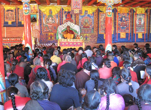 Hor shul Khenpo Gelek Palsang Rinpoche gives a teaching from the front of a lay practitioners' lecture hall on the pasture to a full audience.