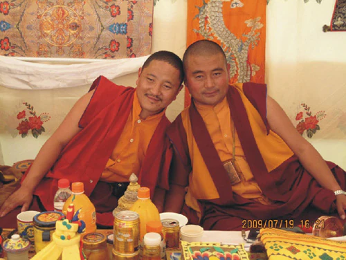 格花堪布與頓珠家族傳人大活佛珠仲身著僧衣，在室內餐桌旁合影。