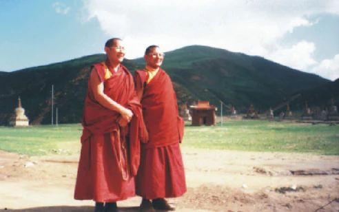 Hor shul Khenpo Gelek Palsang Rinpoche and Great Khenpo Zhuzha of Dzogchen Monastery, identified by the source as a reincarnation of Patrul Rinpoche, stand before a grassland monastery.